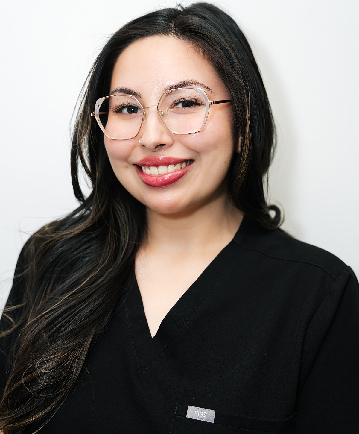 Person smiling in black scrubs against beige background.