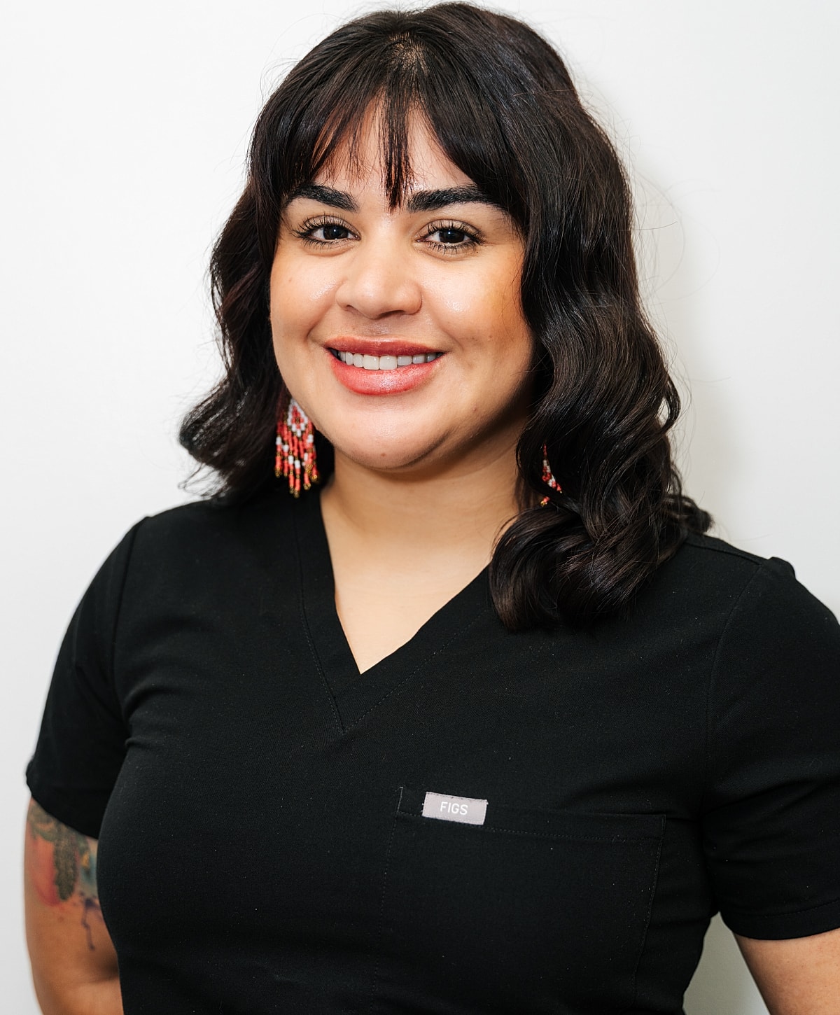 Smiling woman wearing black scrubs in studio.