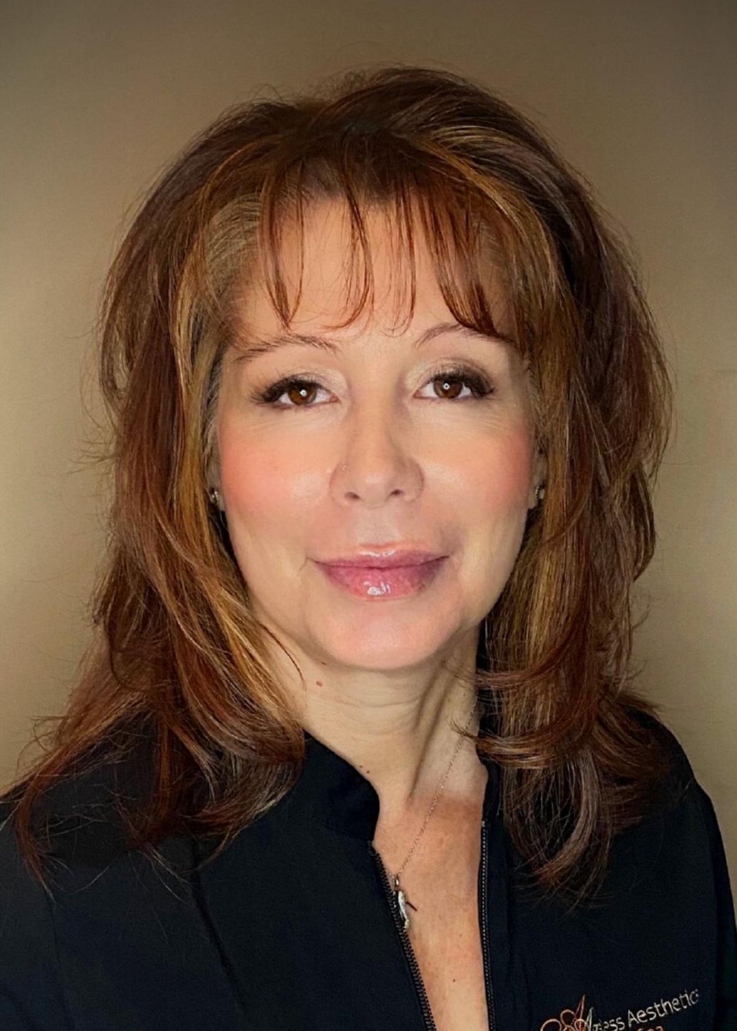 Smiling woman wearing black top against beige background.