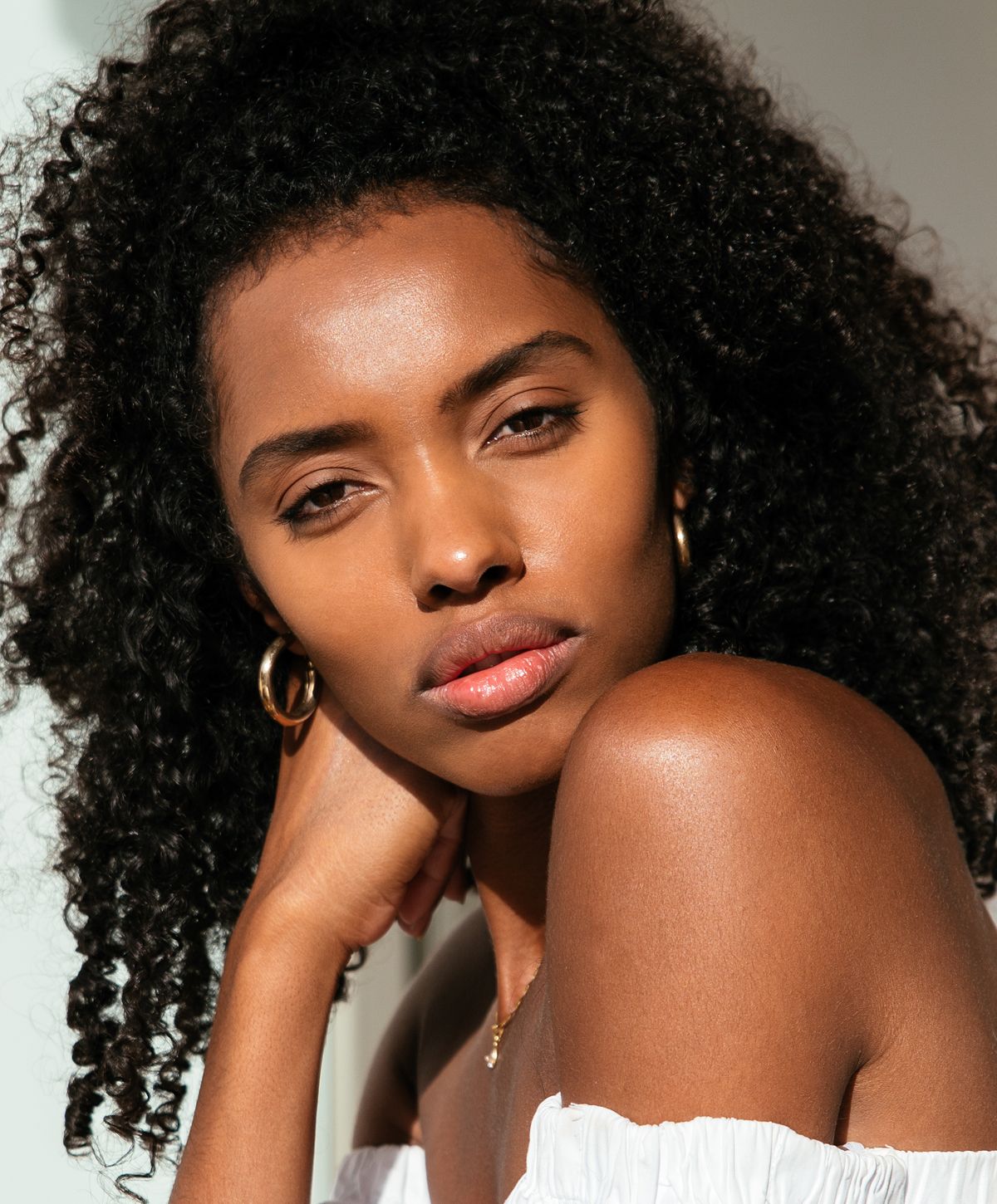 Young woman with curly hair in sunlight.