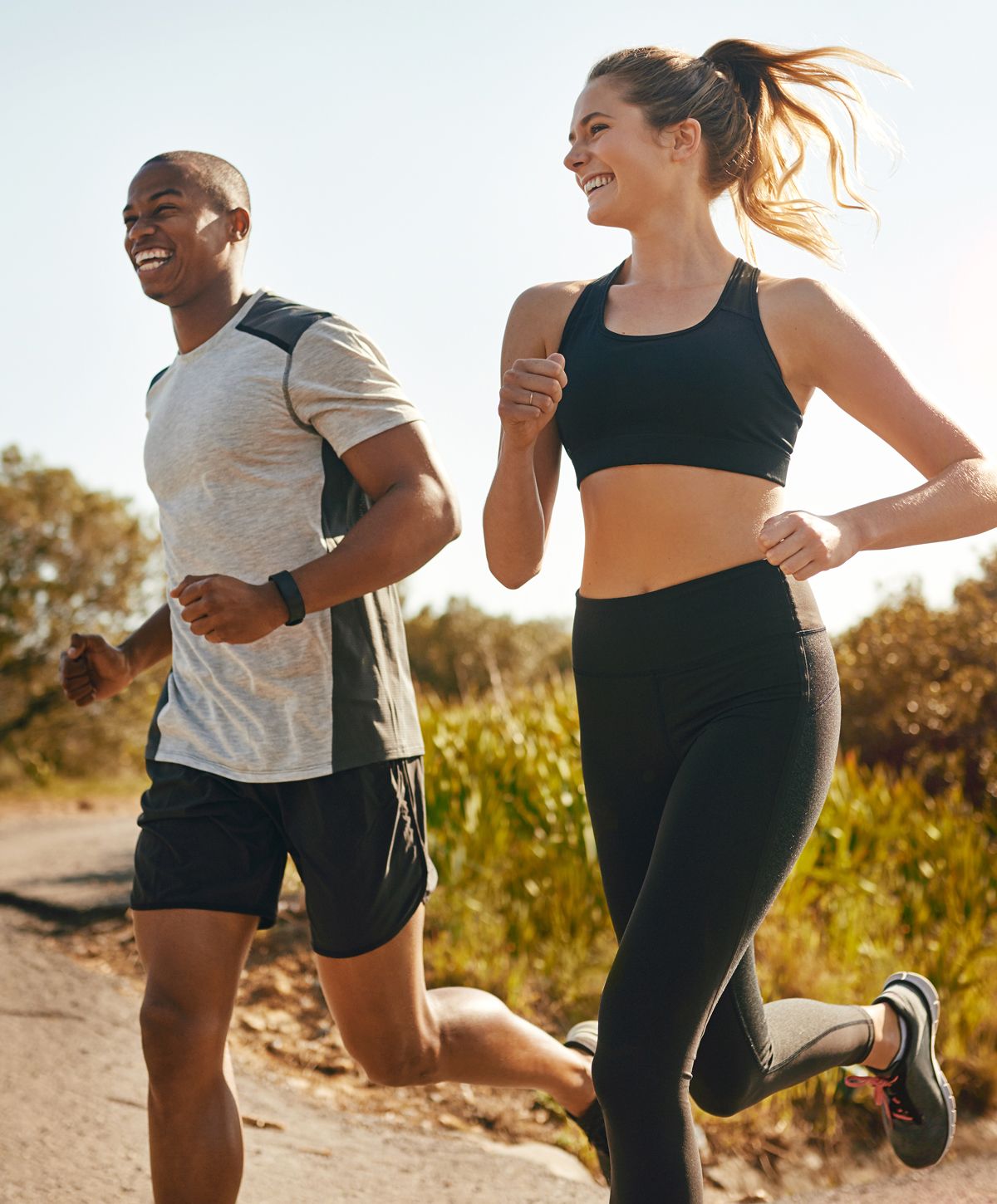 Couple jogging together on a sunny trail.