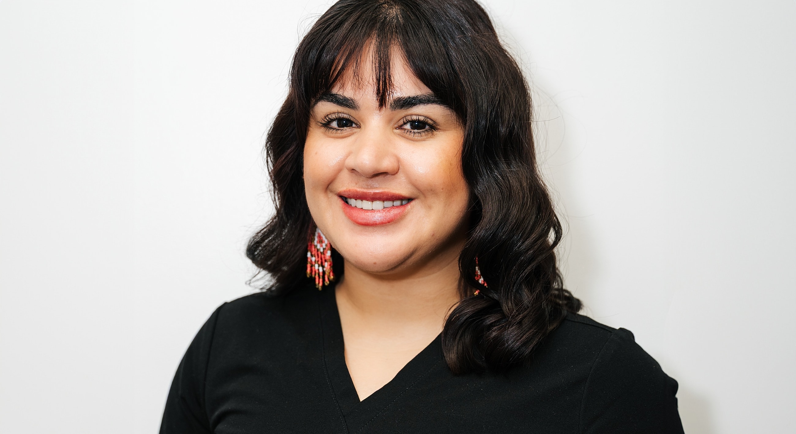 Smiling woman wearing scrubs and earrings.