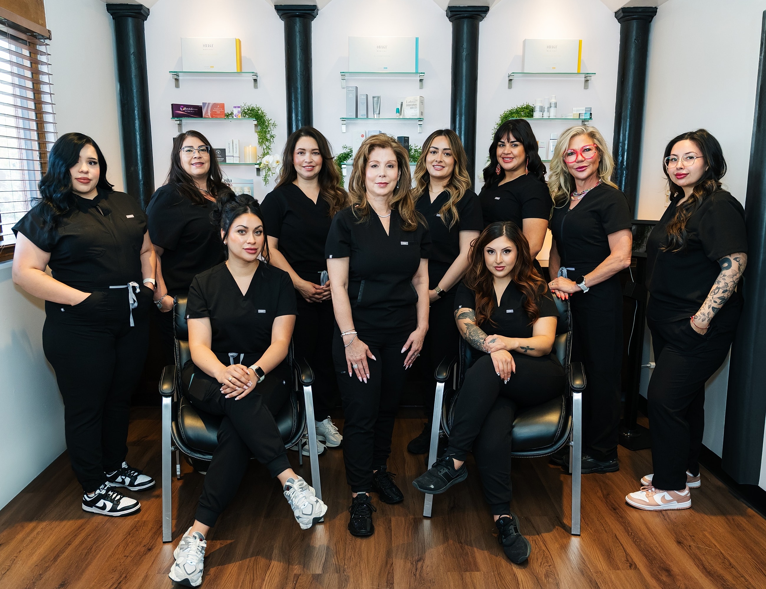 Group of smiling women in black scrubs.