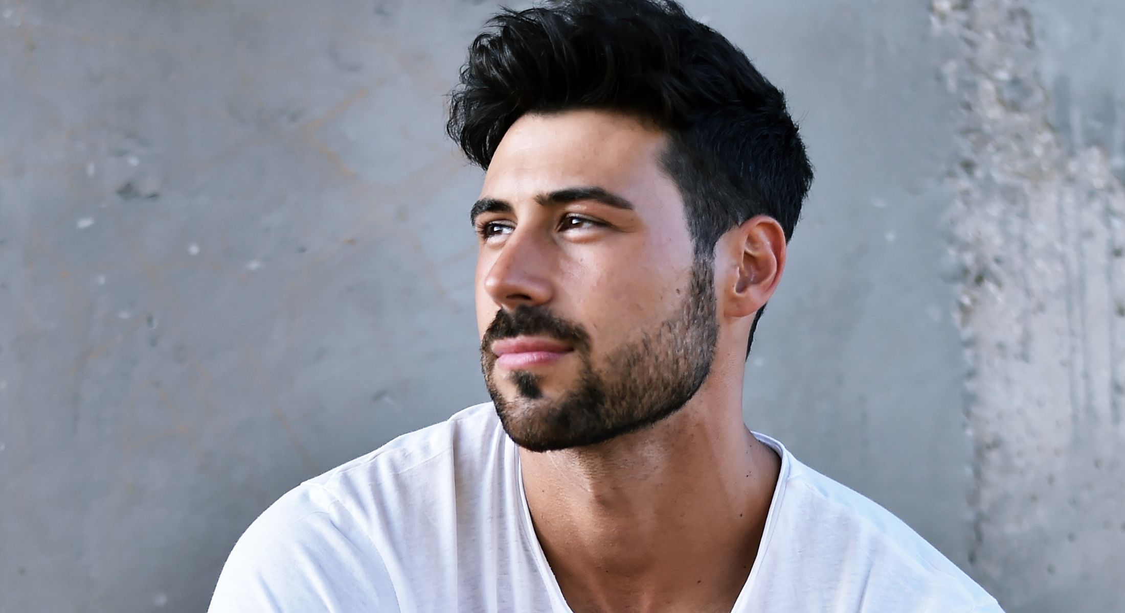 Man with short hair looking thoughtfully to the side.