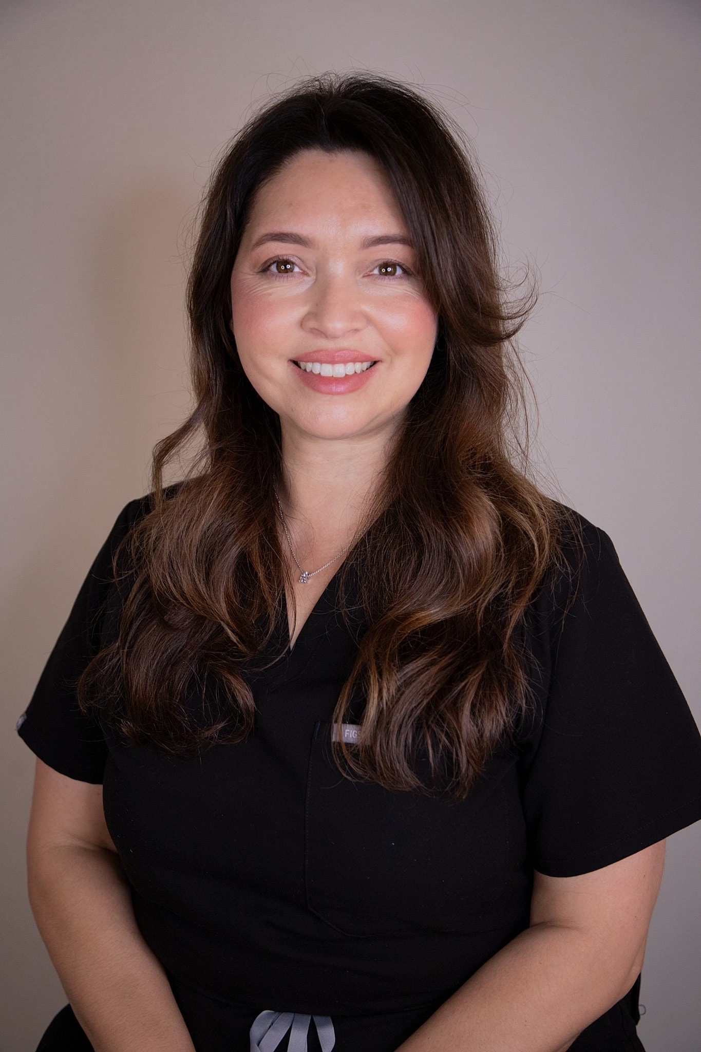 Smiling woman with long hair against a wall.