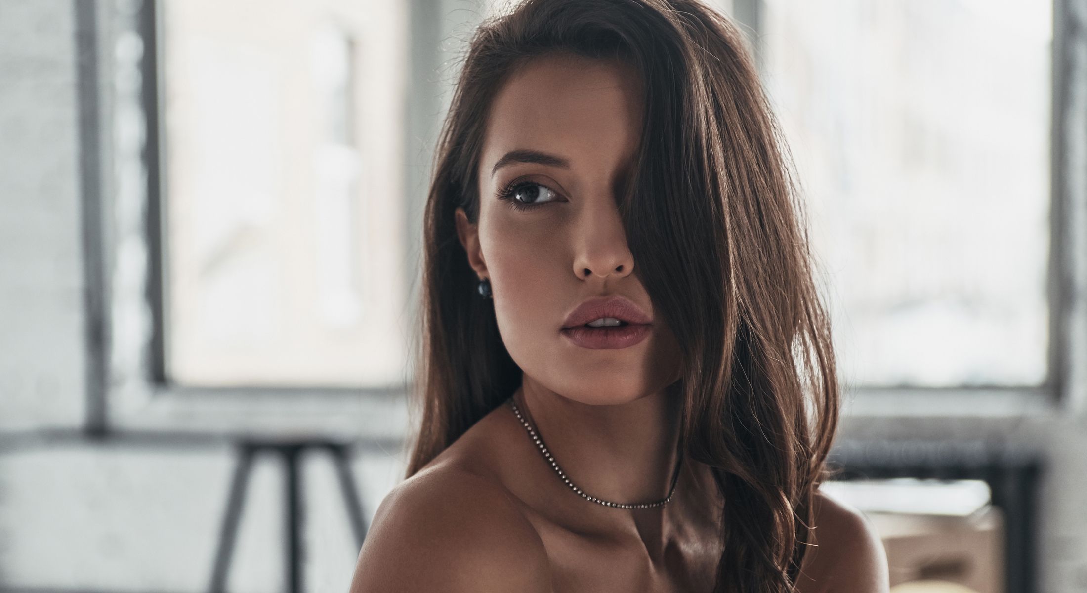 Woman with long hair and earrings in sunlight.