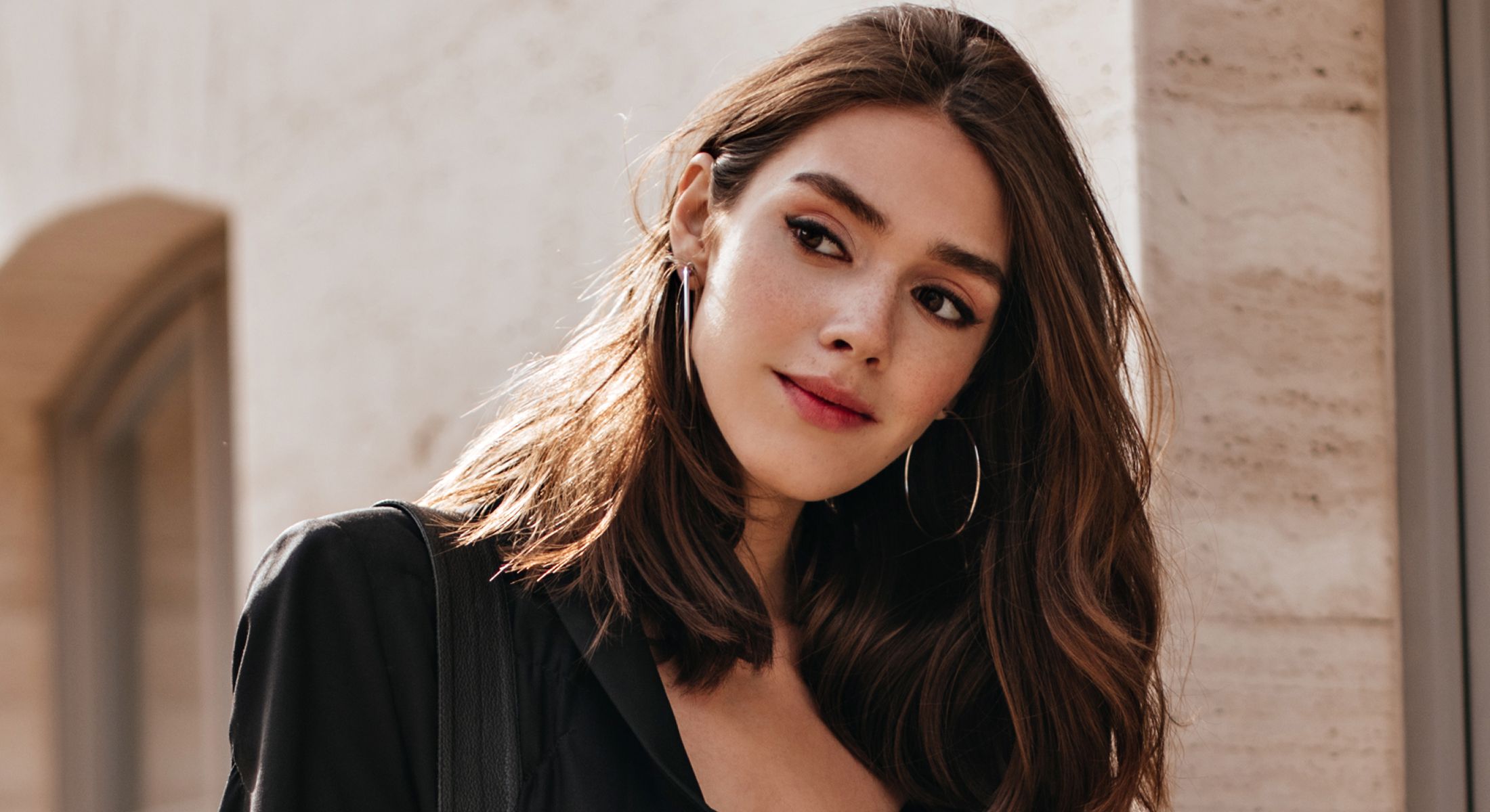 Young woman with long hair and hoop earrings.