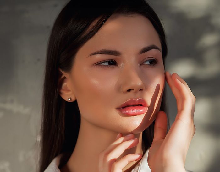 Woman touching her face with soft lighting.