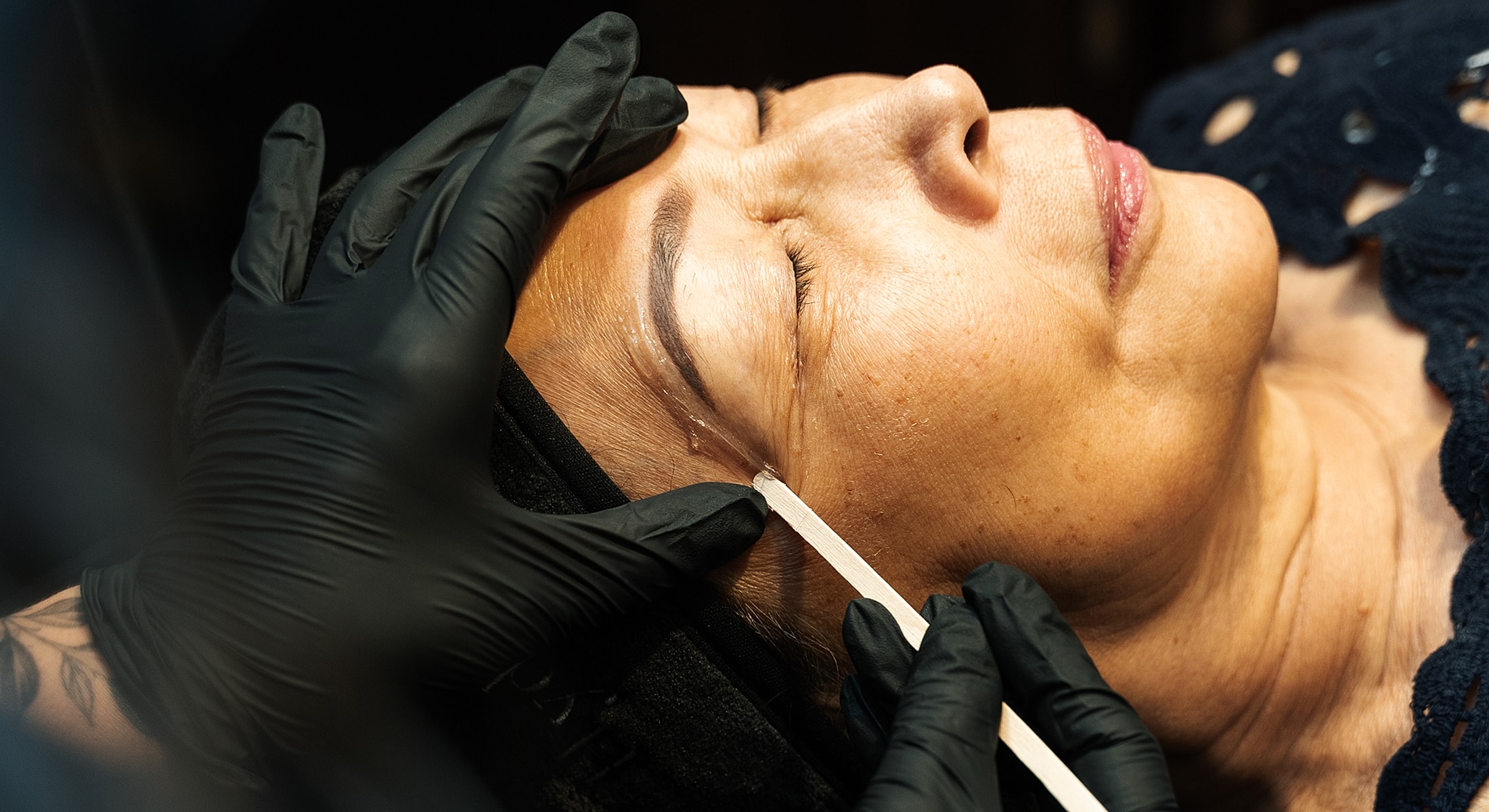 Woman receiving Santa Fe waxing treatment with gloved hands.