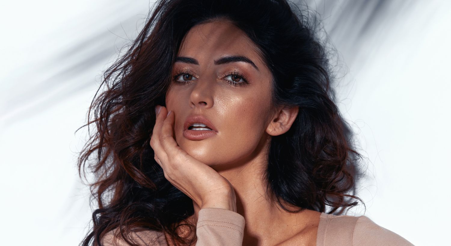 Santa Fe dermal fillers model with curly hair posing thoughtfully.