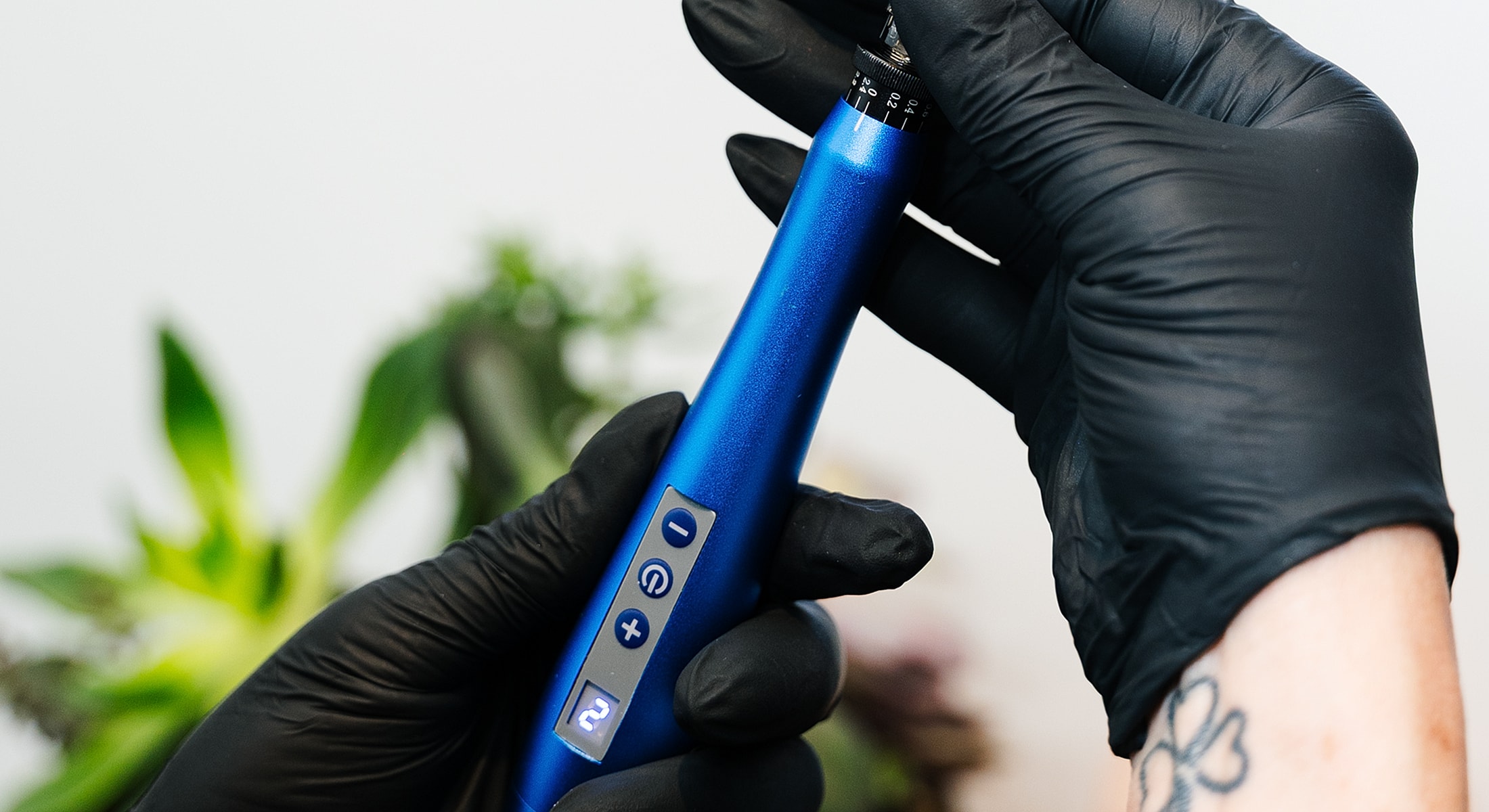 Hand holding a blue tattoo machine.