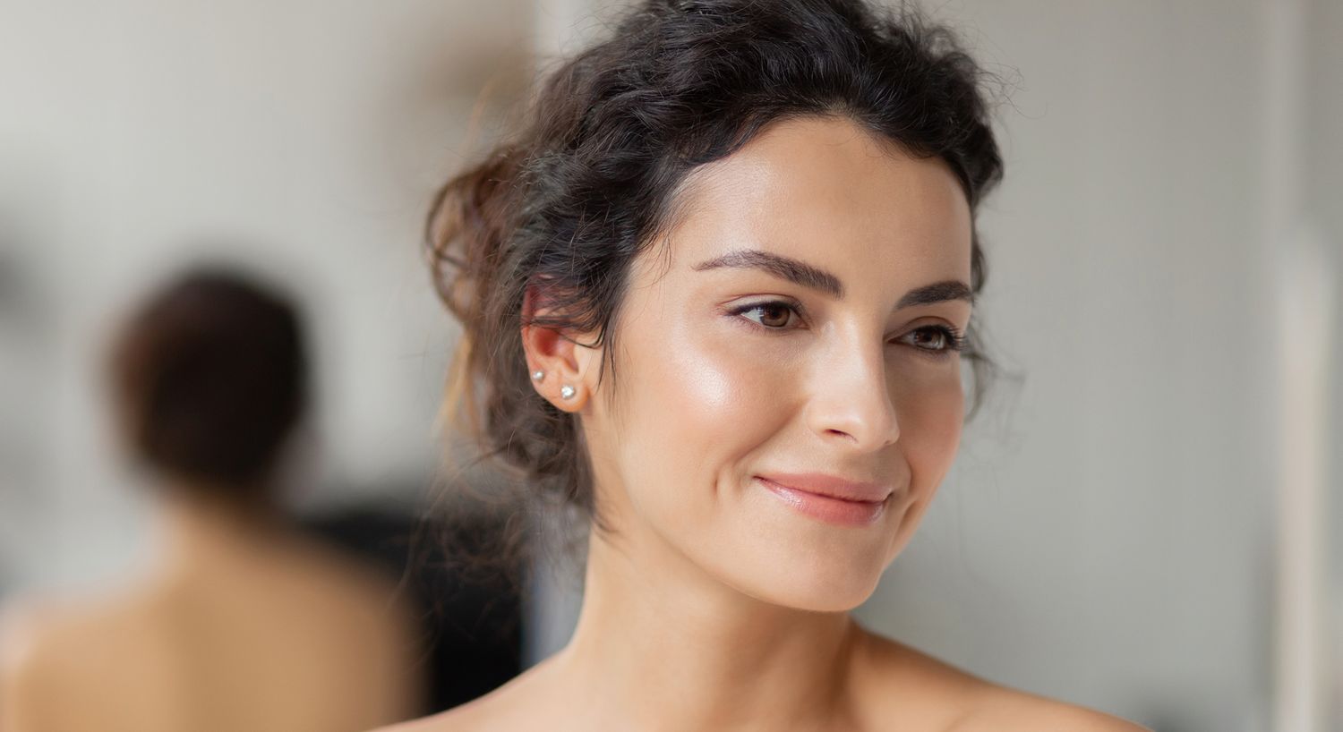 Smiling woman with curly hair and natural makeup.